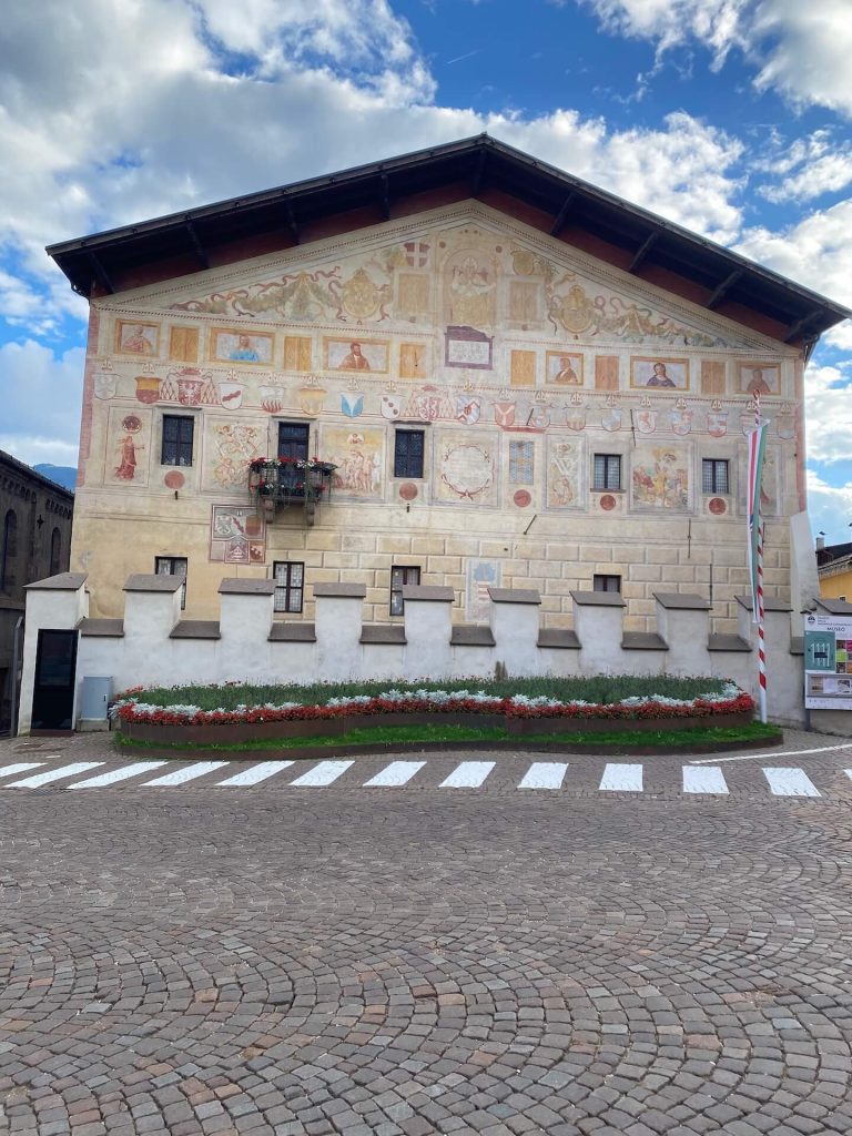 Facciata affrescata del Palazzo della Magnifica Comunità di Fiemme, con muro merlato antistante