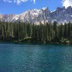 Lago di Carezza con acqua blu-verde, bosco e montagne sullo sfondo