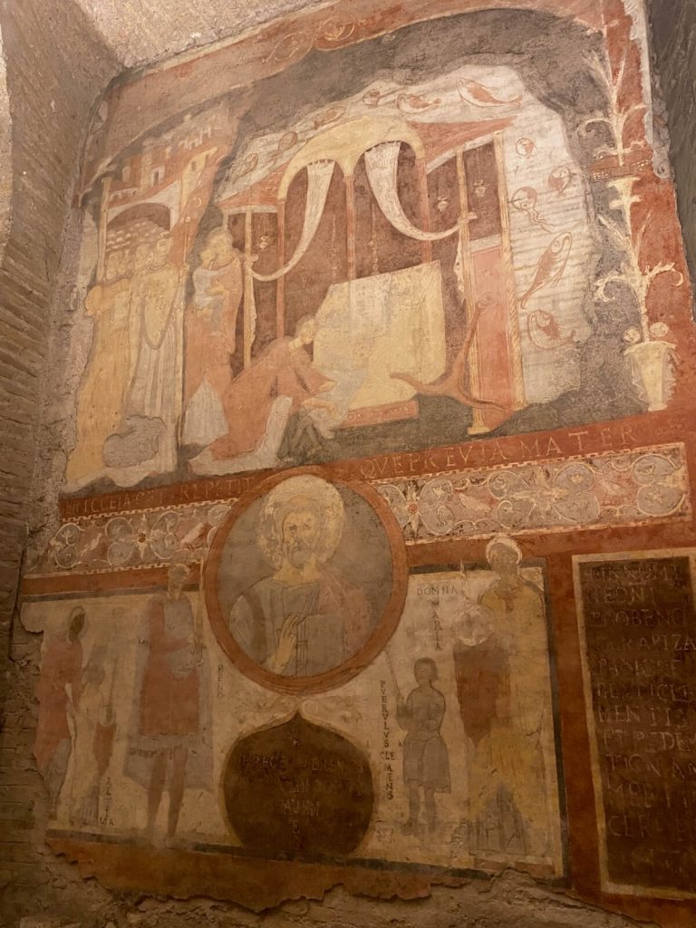 Affresco del miracolo del Mar d’Azov nella basilica inferiore di San Clemente a Roma, con il bambino tra le braccia della madre, figure di vescovi e folla, il mare con pesci e un medaglione con il busto di San Clemente