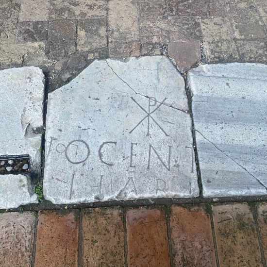 Pietra bianca incisa con monogramma chi rho e iscrizione parziale ‘OCEN’, sul pavimento all’ingresso della basilica dei Santi Quattro Coronati a Roma