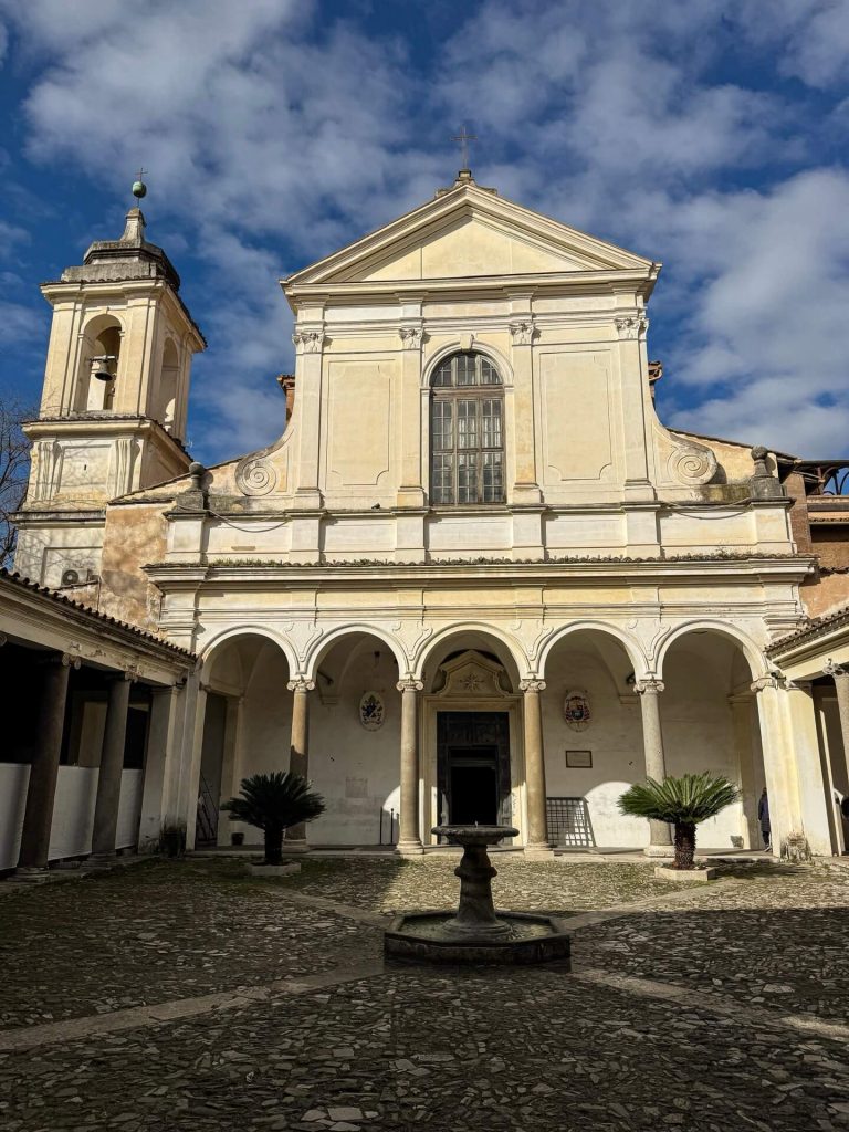 Facciata della basilica di San Clemente a Roma con campanile laterale e atrio a quadriportico con fontana centrale